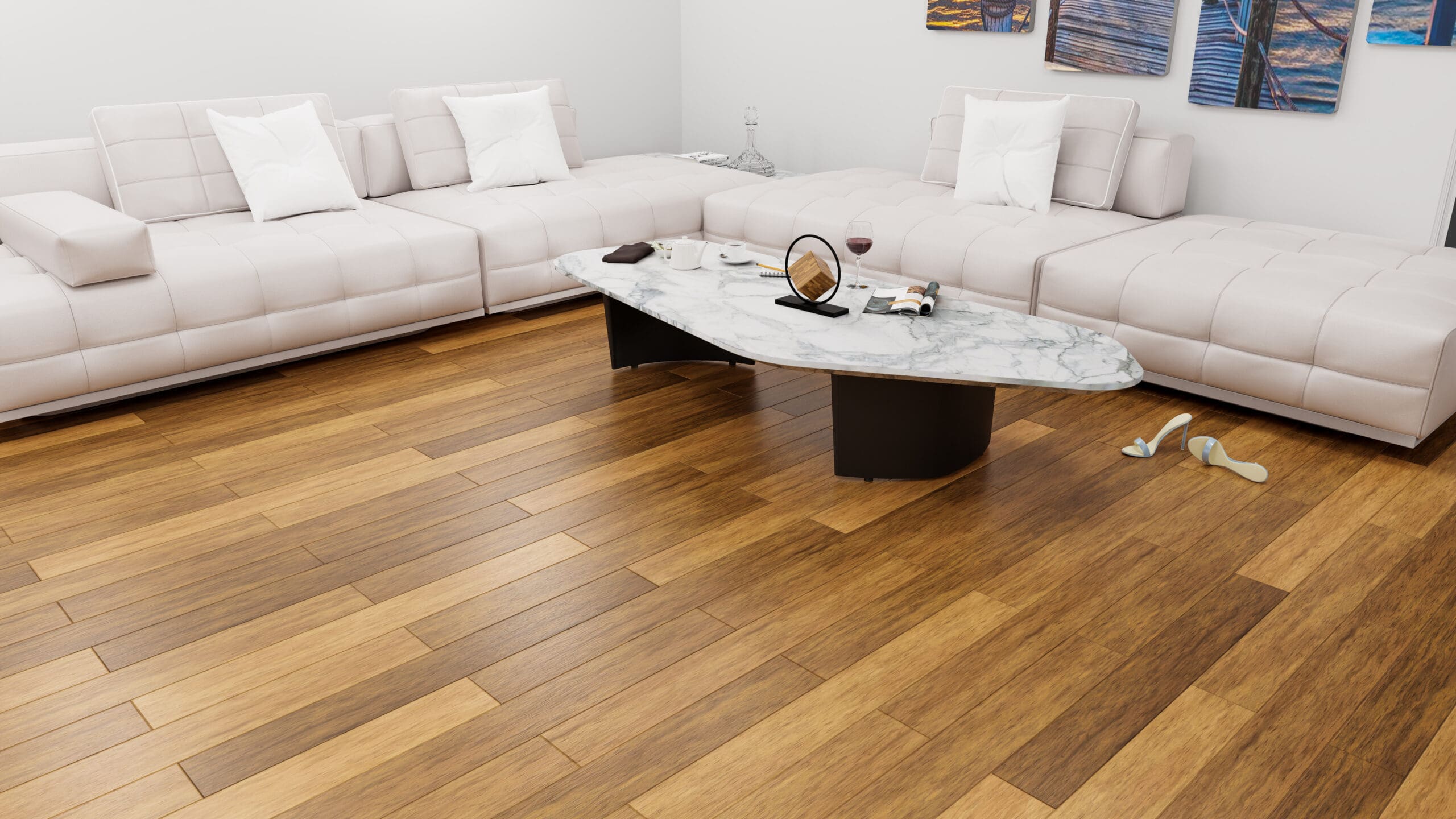 A modern living room with a white sectional sofa, a marble coffee table holding wine and books, and light wood flooring. Wall art decorates the white walls, and shoes are casually placed near the table.